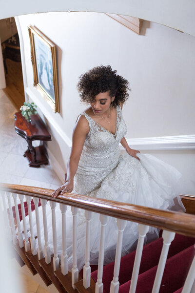 Elegant bride in a luxury wedding gown descending a staircase, captured at a Raleigh, NC wedding venue.