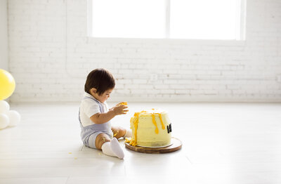 baby sitting on floor with yellow cake