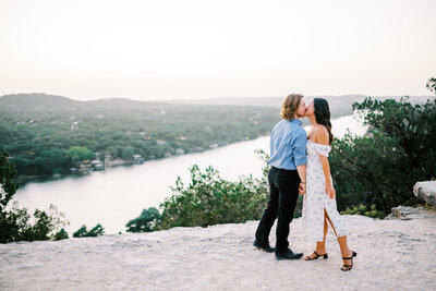 Landscape photo of a couple kissing each other overlooking a body of water