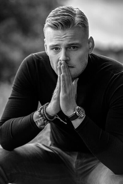 A black-and-white portrait of a young and handsome man wearing a black turtleneck. 