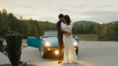 The couple in wedding attire embraces near a vintage car in nature. Capturing romantic moments on their special day.