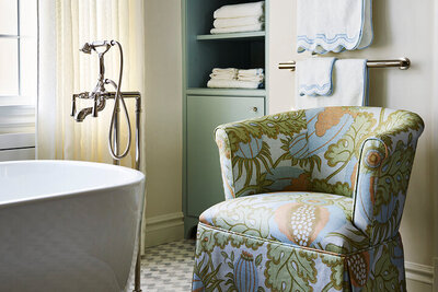 A Boston kitchen and bath designer transforms a Milton primary bathroom with a custom upholstered chair, blending luxury and function in a partial home renovation.