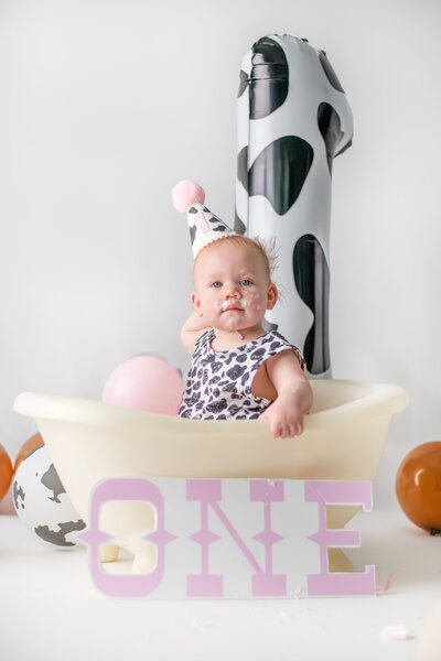 baby girl celebrating first birthday with cake smash