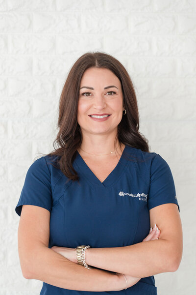 Affordable CoolSculpting in Dallas professional wearing a blue uniform, posing in front of a white wall for a professional headshot.