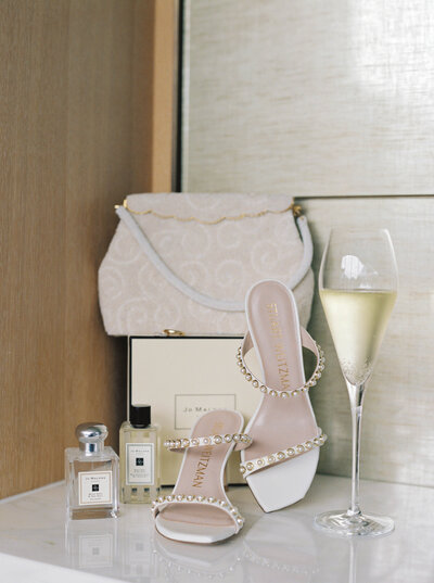 Styled photo shoot of the brides wedding shoes, purse and champagne glass