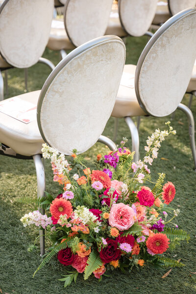 Vibrant Indian wedding ceremony flowers along aisle chairs at the Grand Bohemian Hotel Charlotte, captured by DeLong Photography, Charlotte Indian wedding photographer.