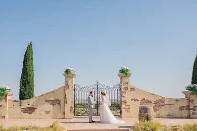 A couple reads their private vows in front of the gate at Bella Terre Vineyard. True color wedding photo by Claire Katan.