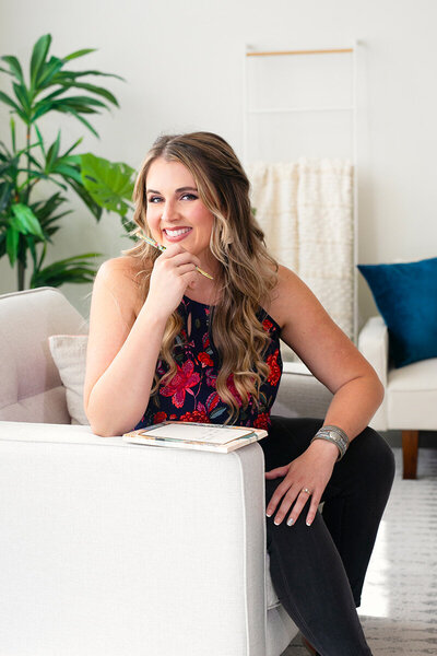 Natasha smiling on a white couch with a bright patterned flower shirt