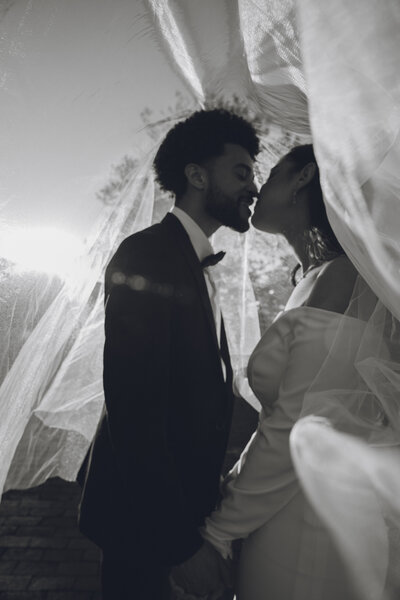 Black and white photo of couple kissing under veil at Philadelphia wedding