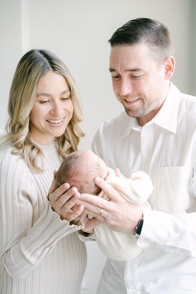 neutral toned newborn session of a new mom and dad holding their new son