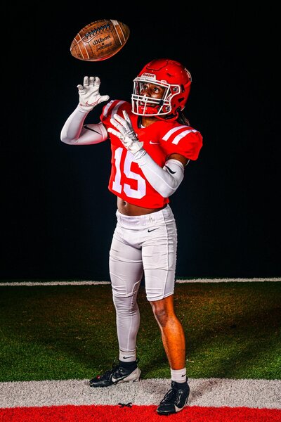 Senior Football Player Throwing Ball in Air