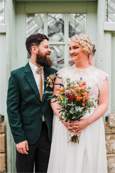 Bride and groom in a white wedding gown and black tuxedo staring into each other’s eyes.