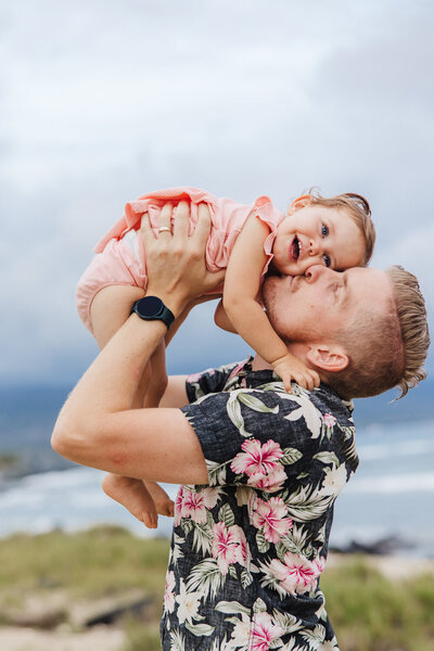 dad kissing baby on beach in hawaii