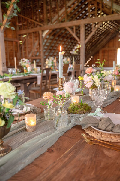 Long wooden wedding tables decorated with flowers and candles