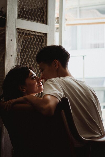 couple looking into one another's eyes as one partner sits on the other partner's lap