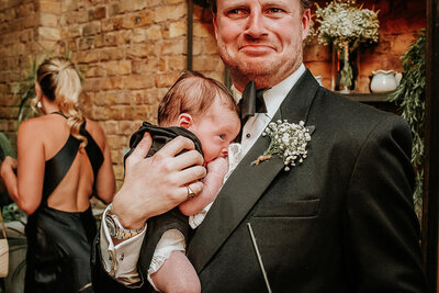 Groom laughing holding new born