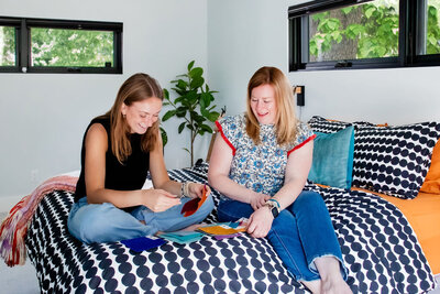 Two women on bed looking at color swatches