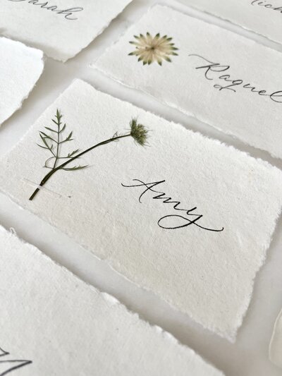 Place cards with pressed flowers and black ink calligraphy for event at Mayflower Inn and Spa in Washington, Conneticut