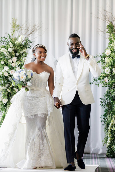 A black couple is happily walking down the aisle after their wedding ceremony at the Down Town Club in Philadelphia