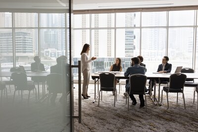 Businesswoman presenting to colleagues in modern office conference room