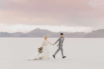 A groom holds his bride hand as they run across the Bonneville salt flats near utah, on their wedding day. 