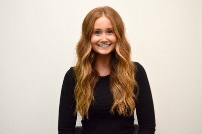 A portrait of Abigail Moreland, a stylist at 212 Salon, Spa, & Barbershop, wearing a black top and smiling at the camera.