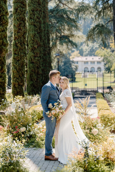 A bride and groom are surrounded by a whimsical meadow-inspired installation  with Villa Montalvo in the background.