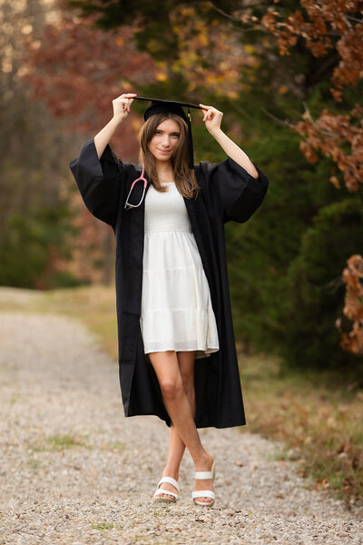 Cap and Gown Girl in field with legs crossed at the ankle