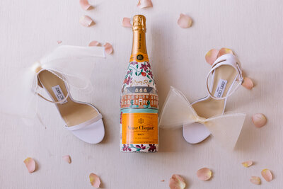 A bottle of Brut Champagne  sits between wedding shoes
