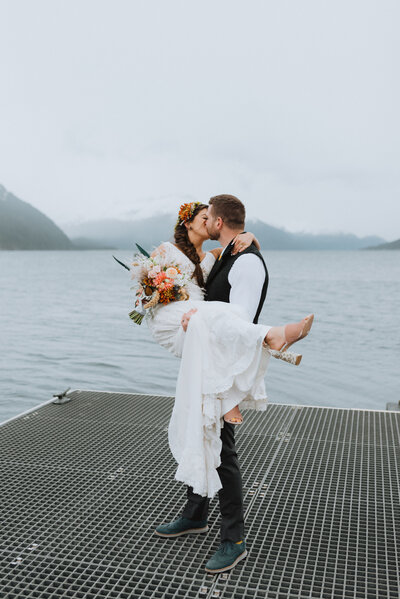 groom holding up bride on the dock