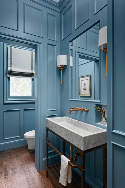 Blue painted bathroom with white marble sink and gold accents