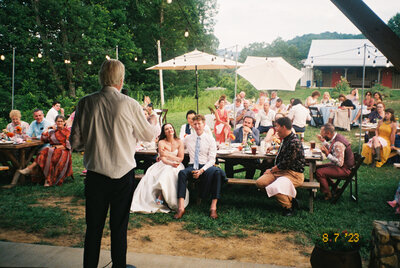 The hits keep on coming as the bride and groom listen to a speech during their reception at wedding venue Paint Rock Farm in North Carolina, by wedding photographer My Sun and Stars Co.