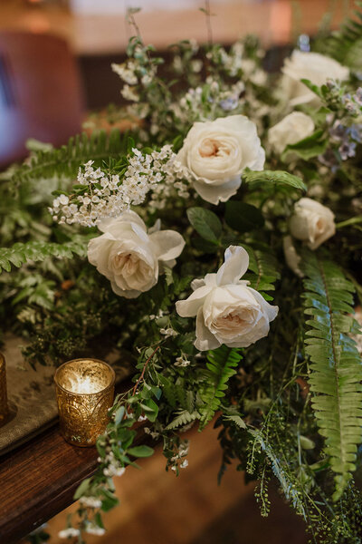 White rose and greenery floral arrangement with candles