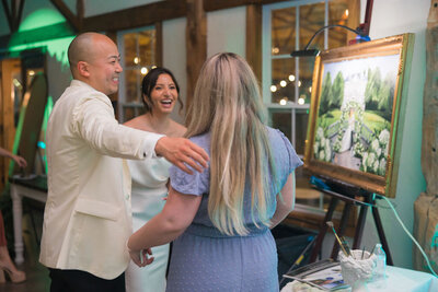 A bride and groom smile as they see their live wedding painting created by Brittany Branson at Great Marsh Estate