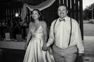 bride and groom walking into wedding reception while holding hands