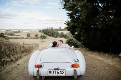 A bride and groom kissing in the back of their car as they drive away, photographed by wedding photographer michelle kelly