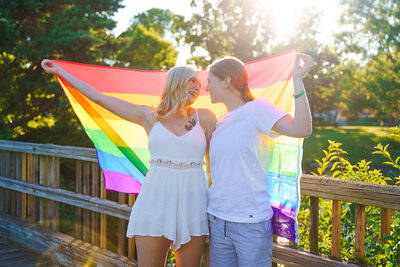 LGBTQ+ couple looking lovingly at each other while holding up a rainbow flag.