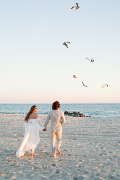 Bride and groom running on the beach in New Jersey