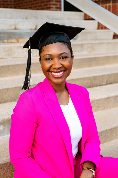 College grad wearing black cap and hot pink suit jacket