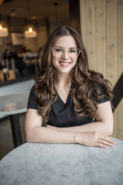 Photographer Lana Stewart leaning against table at Fika cafe in Puyallup