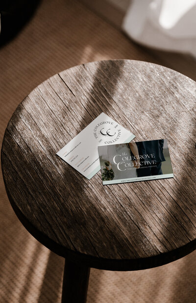Business cards for a wedding photographer sitting on a wooden table in the sunlight