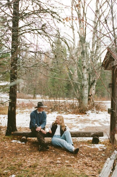 couple sitting and smiling at each other near lake mcdonald