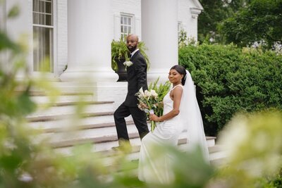 Alix & Ob holding hands as they pose for portraits on the steps of court manor in virginia on a n overcast day in the spring