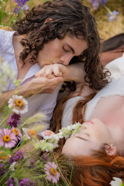 A person laying next to their partner kissing their hand