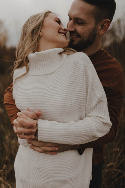 Couple standing kidding for engagement photos outside 