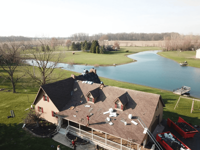 Black Bear Roofing team working on a house roof near a lake, showcasing scenic surroundings.