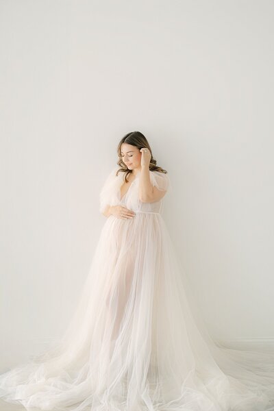 Pregnant mother in a cream floral dress holds her baby belly outside, Indianapolis Photographer