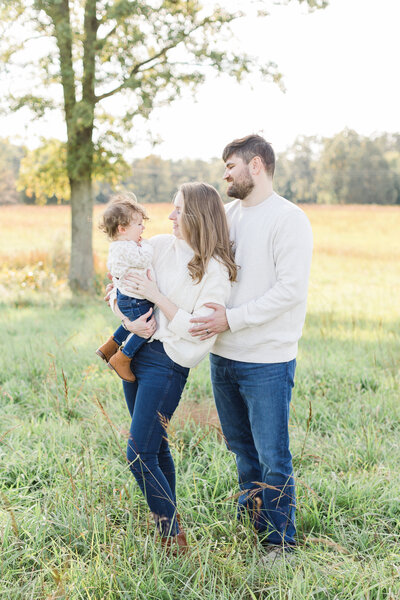A Northern Virginia Family Photographer photo of family smiling at each other outside in tall green grass