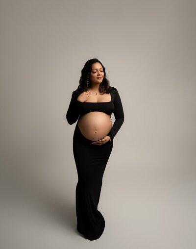 Studio image featuring a two-piece black maternity set with exposed belly