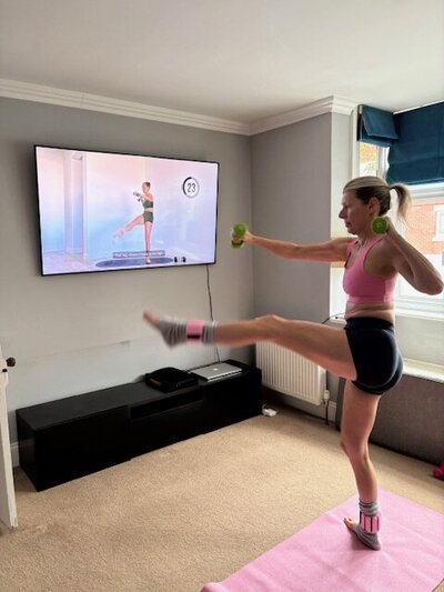 Women doing a workout in her living room with workout videos streaming to her TV